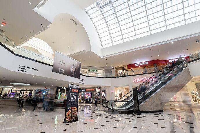 An escalator climbs from a shiny floor within an atrium of a mall.