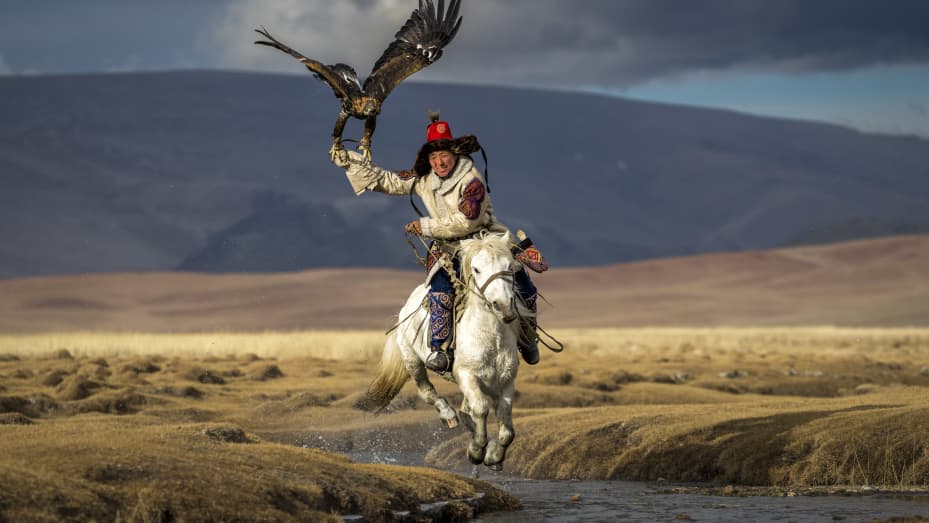 A hunter and his eagle on horseback in the grasslands outside of Bayan-Olgii, Mongolia.